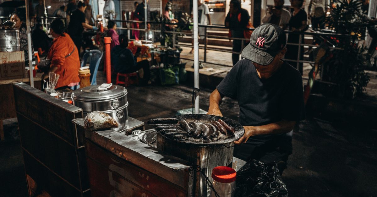Street food stall with a vendor cooking and customers waiting nearby
