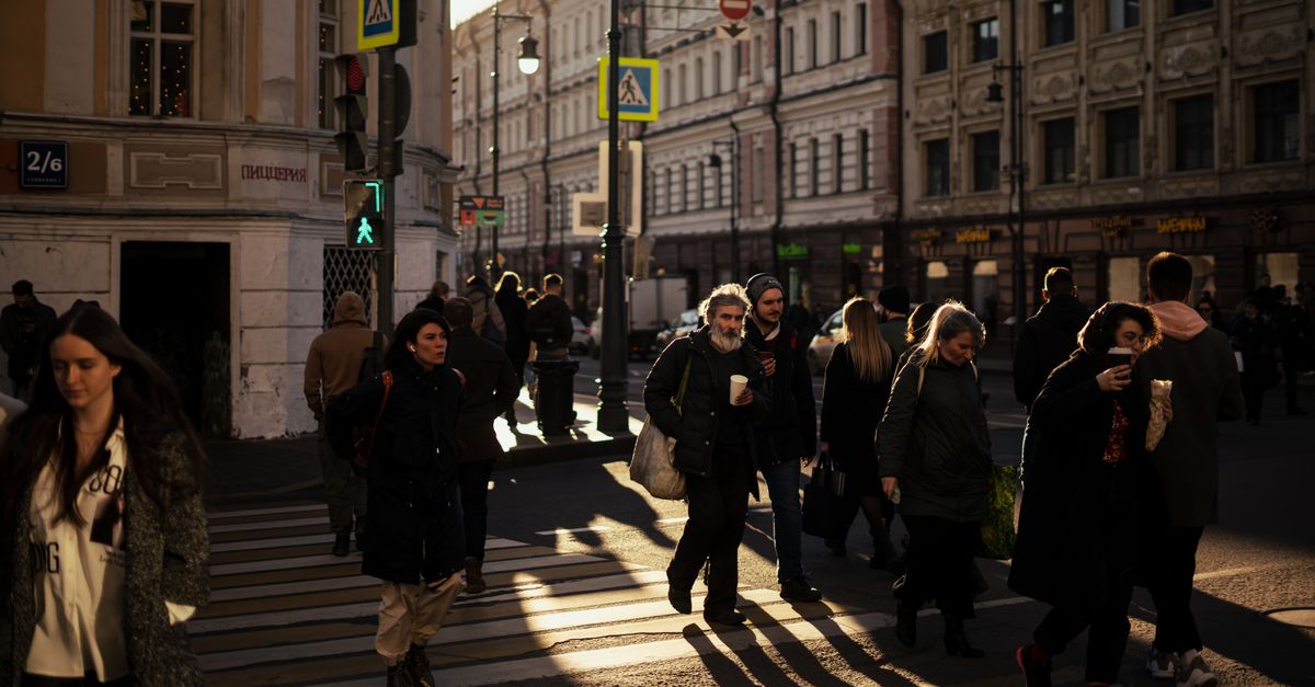 Calle concurrida de la ciudad con peatones y edificios bajos bajo una luz cálida de la tarde