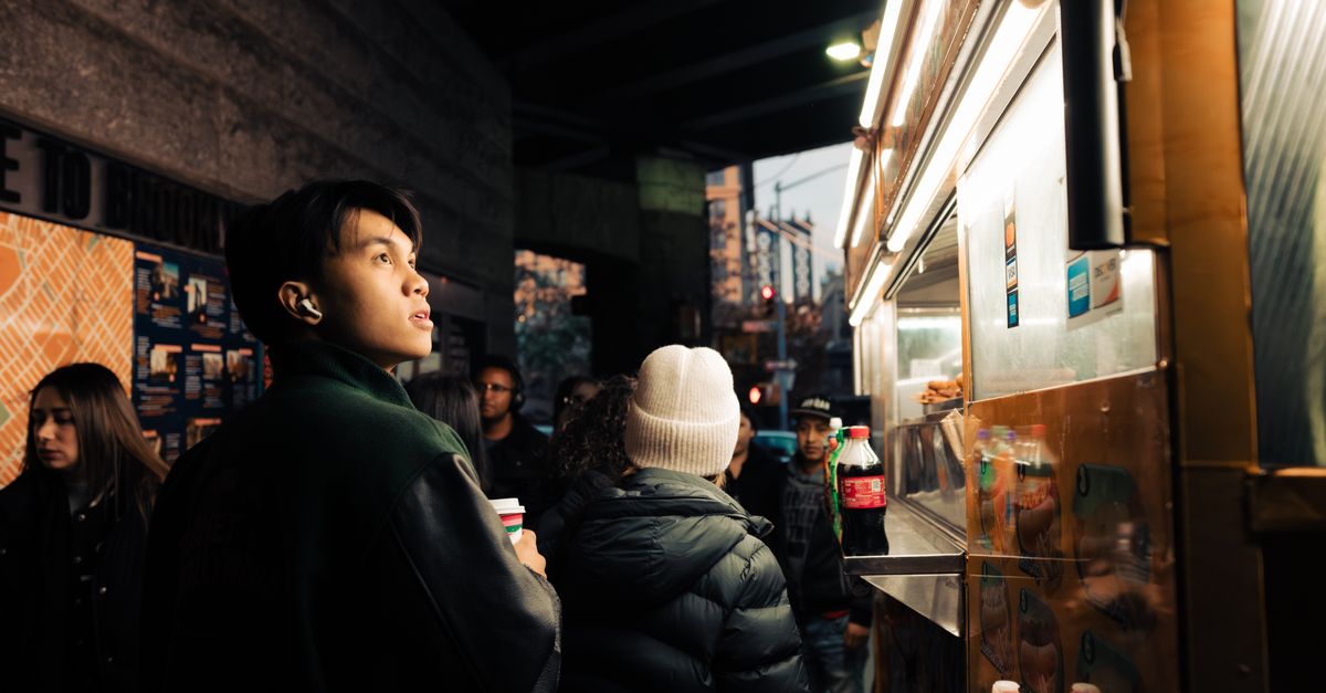 Clientes reunidos alrededor de un puesto de comida callejera al atardecer