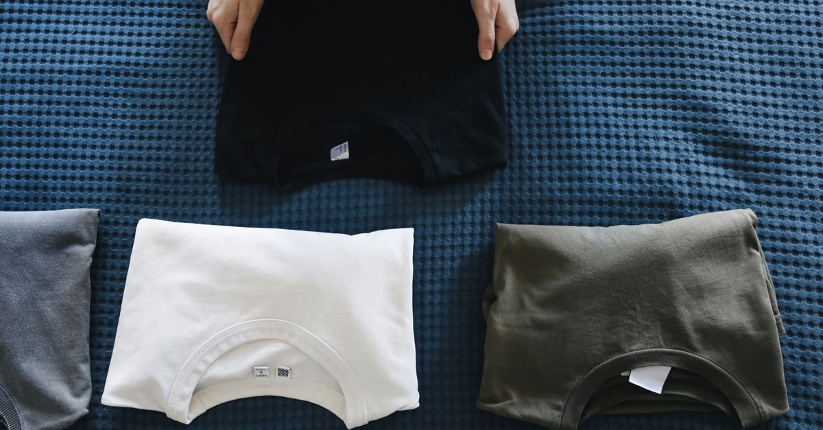Camisas ligeras dobladas y pequeños artículos de viaje colocados junto a una maleta